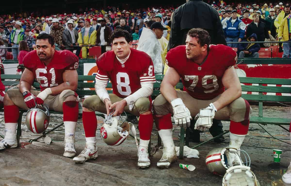 A film photo of three benched players, watching from the sidelines.